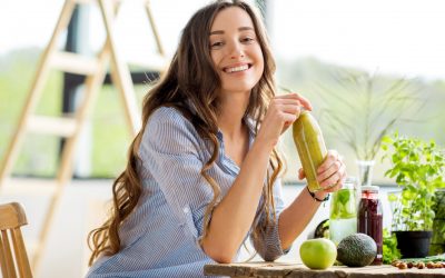 Beautiful happy woman sitting with drinks and healthy green food at home. Vegan meal and detox concept